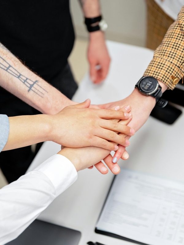 Close-up of a diverse team stacking hands on an office desk, symbolizing teamwork.